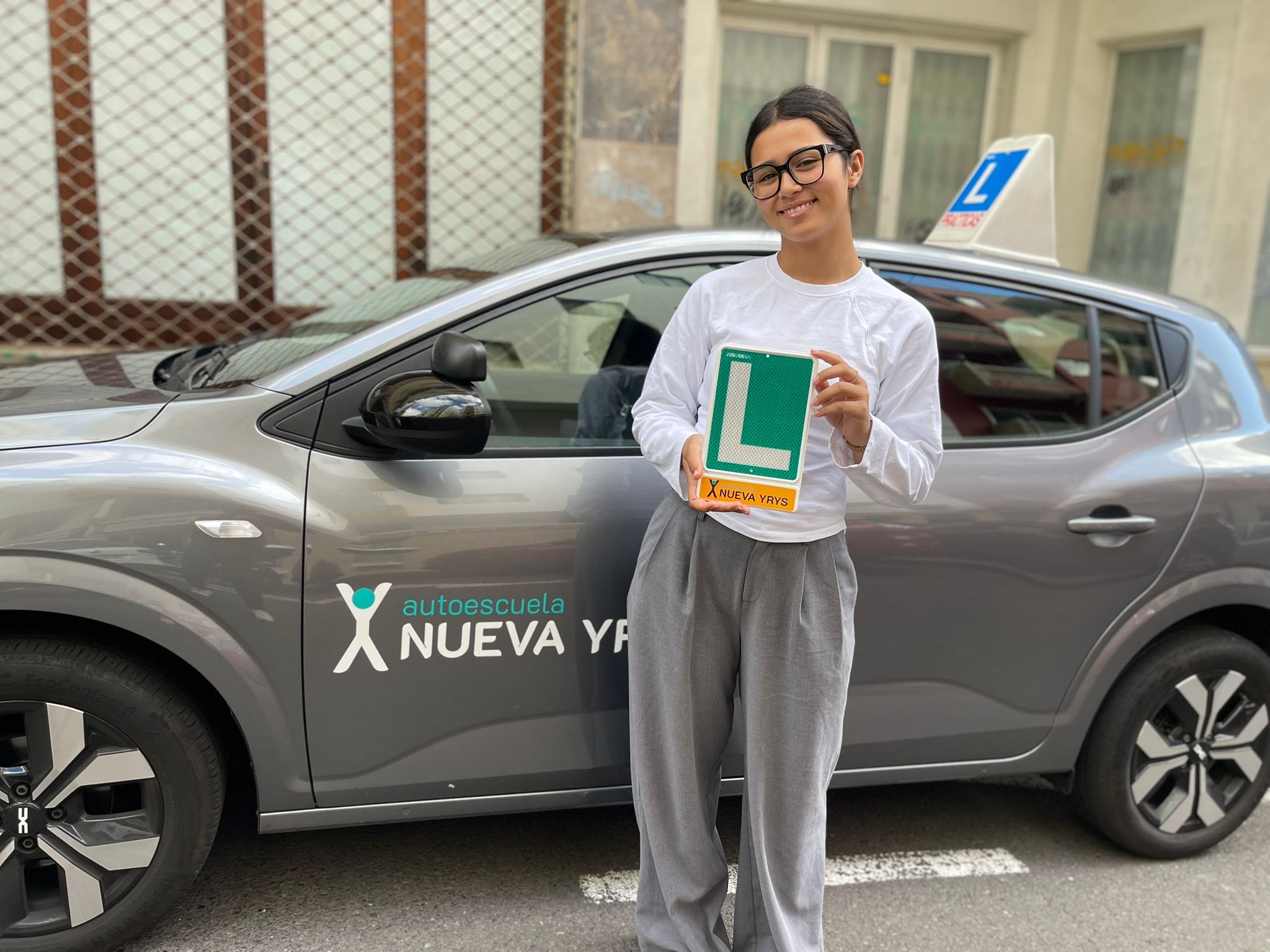 Alumna recién aprobada con su placa L junto al coche de la Autoescuela Nueva Yrys en Santa Cruz de Tenerife