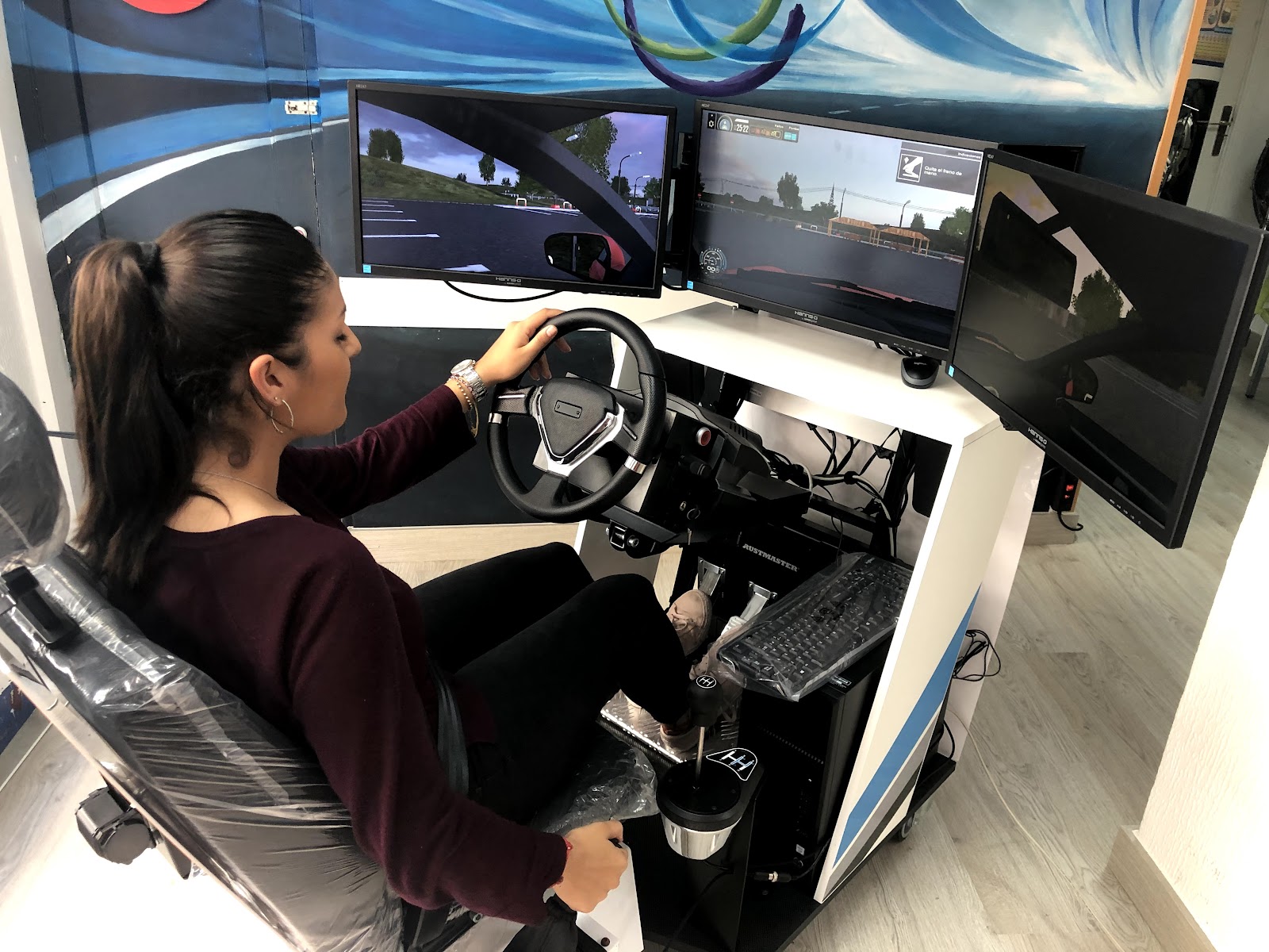 Alumna practicando en el simulador de conducción de tres pantallas de la autoescuela